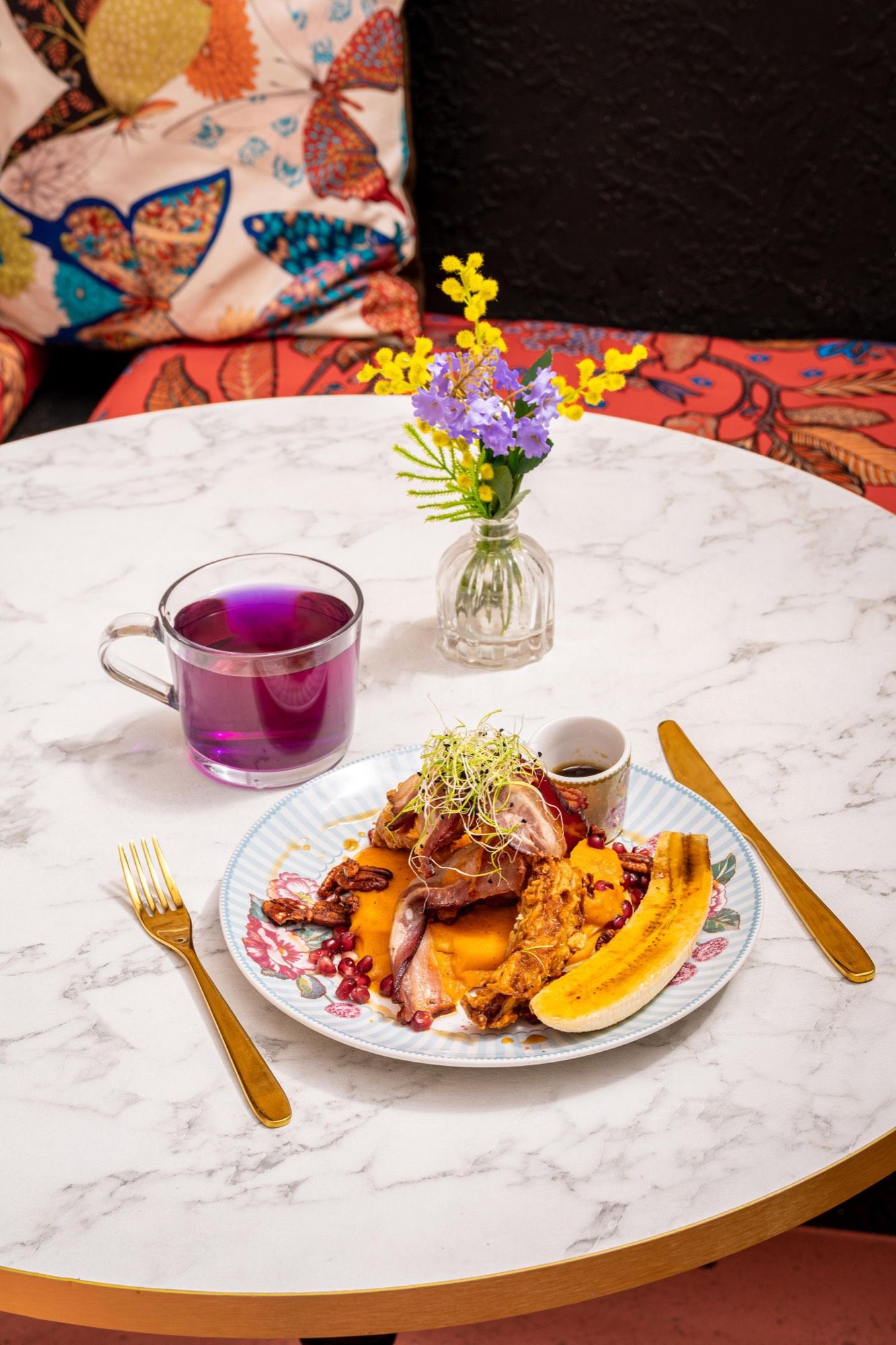 Assiette de brunch salée-sucrée et thé violet à la fleur de pois papillon, sur la banquette à papillons de PEACH