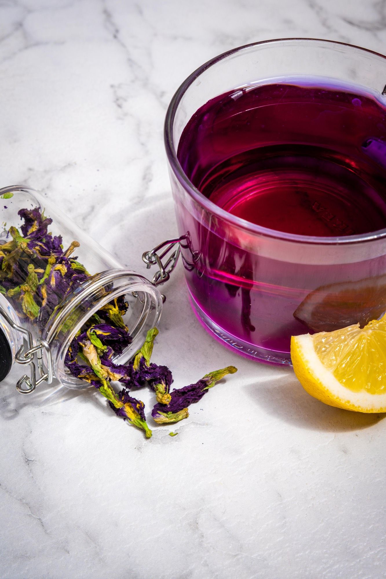 Infusion violette à la fleur de pois papillon servie avec son quartier de citron, en gros plan