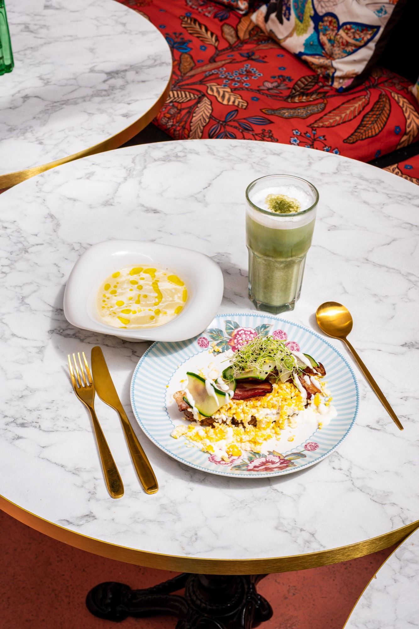 Œufs brouillés au bacon et matcha latte servis sur une table en marbre chez PEACH