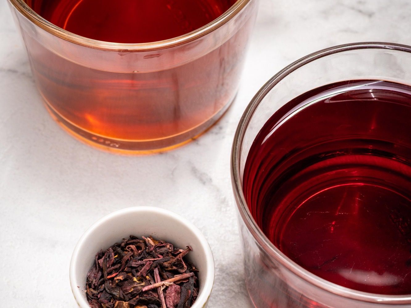Deux infusions d’hibiscus aux reflets rouge et ambre, fleurs séchées en coupelle